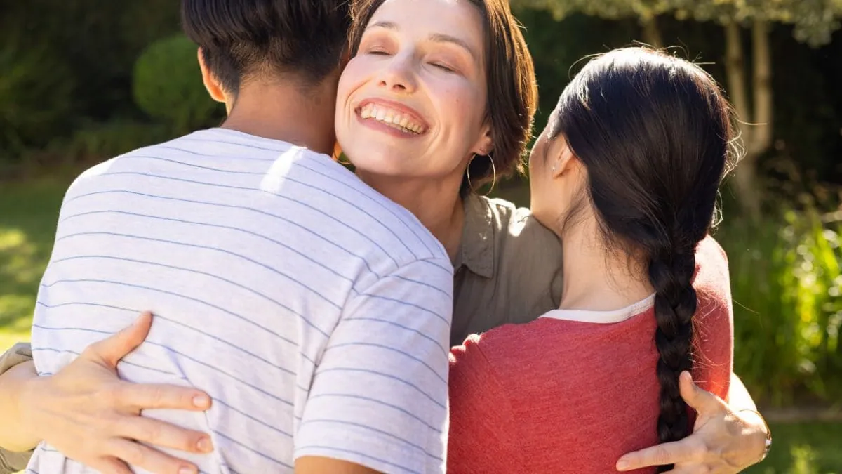 Una mujer abraza a su familia al aire libre, una imagen de la asistencia familiar integral del seguro de decesos