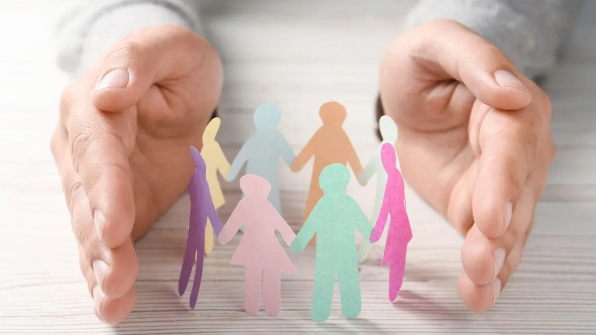 Dos manos resguardan un círculo de figuras de personas, una imagen para la guía sobre ¿Es obligatorio el seguro de decesos?
