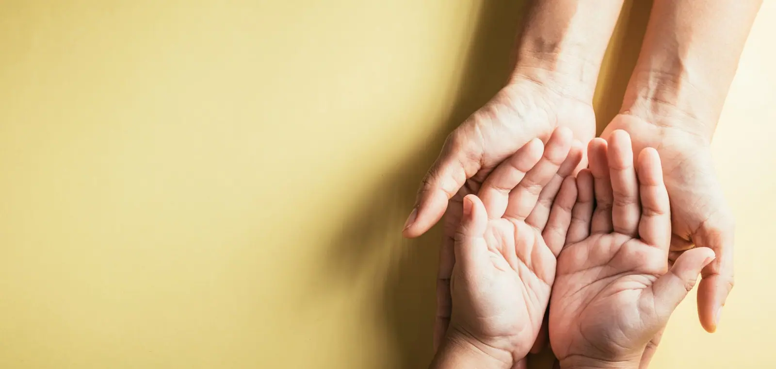 Unas manos adultas sostienen con cariño las manos de un niño, una imagen del seguro de decesos en Ávila
