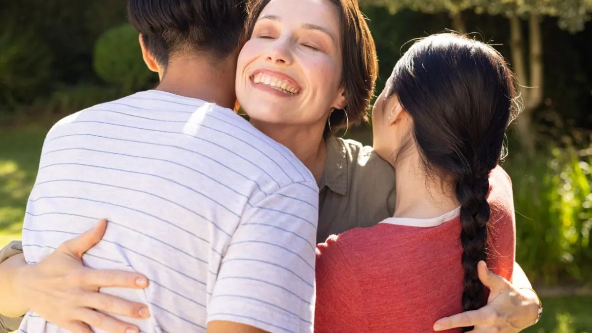 Una mujer abraza a su familia al aire libre, la protección familiar del seguro de decesos en Girona