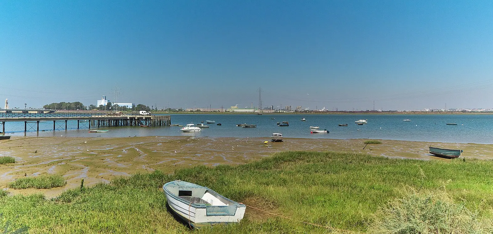 La ría del Tinto en Huelva, con el muelle y las barcas en la orilla, una imagen del seguro de decesos en Huelva