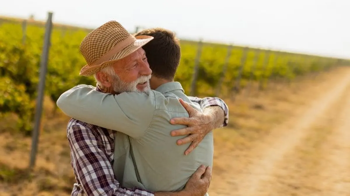Un padre mayor y su hijo caminan juntos entre viñas, el seguro de decesos para mayores en Huesca