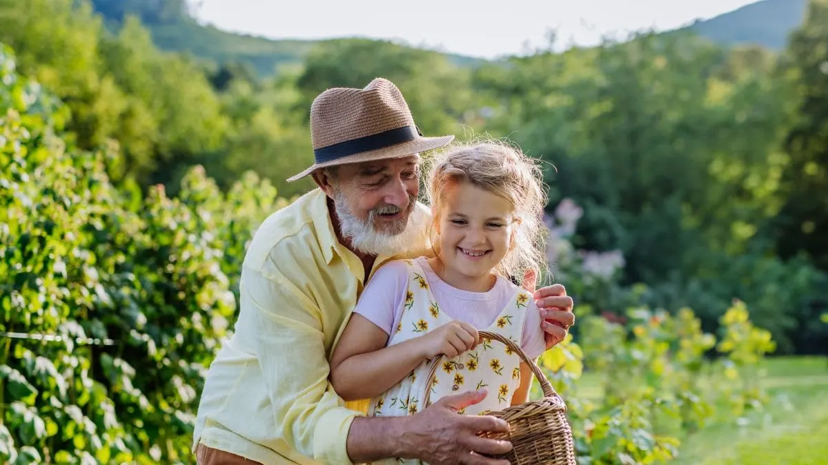 Un abuelo y su nieta comparten un momento en el jardín, una imagen para la guía sobre seguro de decesos para mayores de 70 años