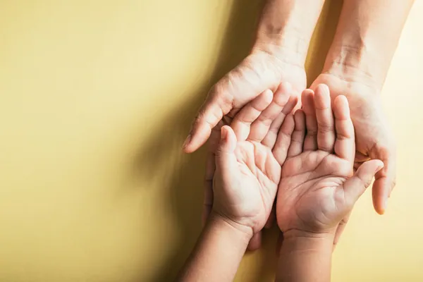 Tengo dos seguros de decesos: unas manos adultas sostienen con cariño las manos de un niño